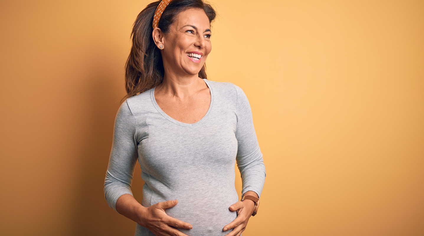 middle aged pregnant woman holding belly