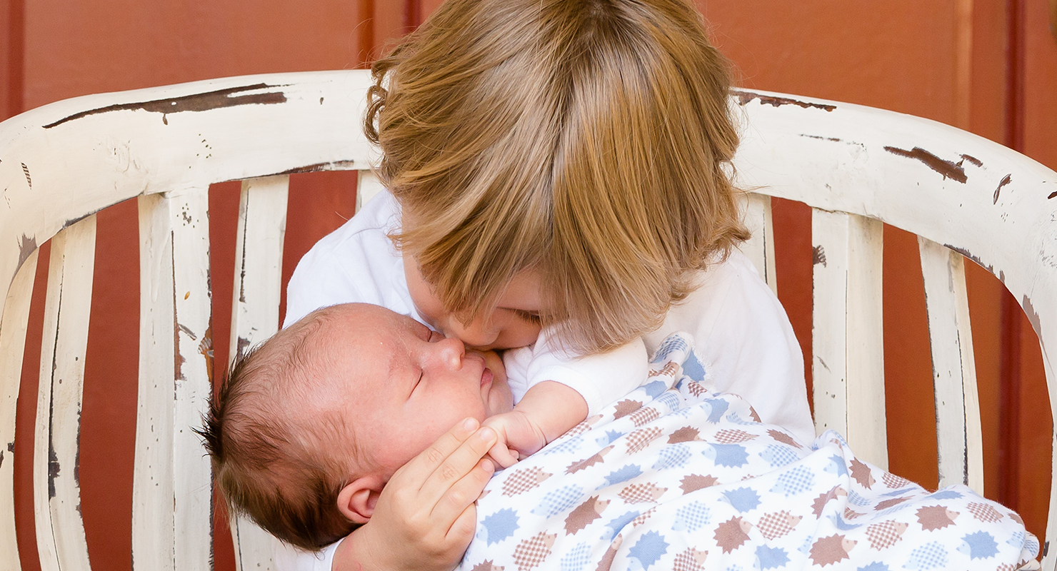 toddler kissing newborn sibling