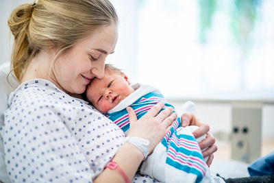 mom holding swaddled newborn in hospital