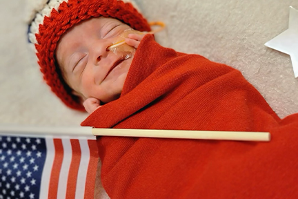 NICU baby in red blanket July 4