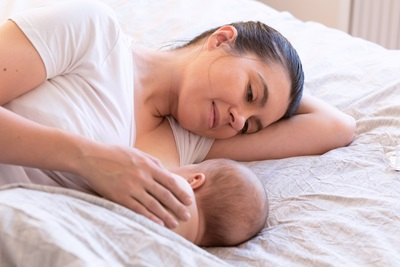 mom breastfeeding newborn in bed