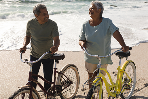 mature couple walking bikes on beach