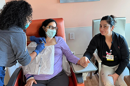 Patricia holding nurse's hand while receiving IV infusion therapy