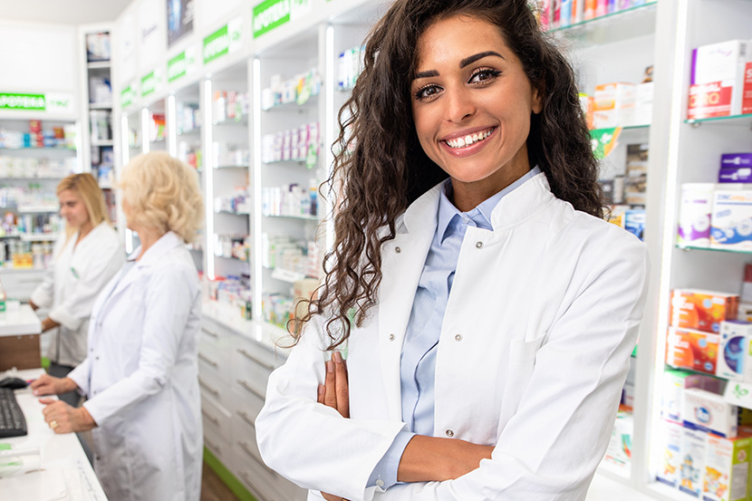 Woman inside pharmacy with arms cross smiling.