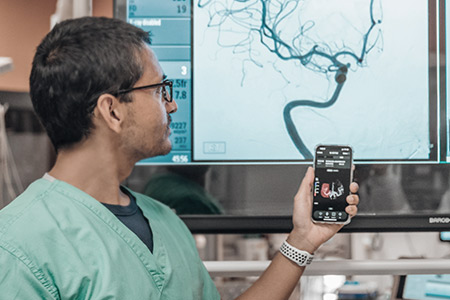 Doctor Mehta in front of a display of an aneurysm 