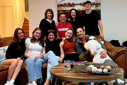 Scott smiles while taking a photo with his family in their living room, sharing a joyful moment together.