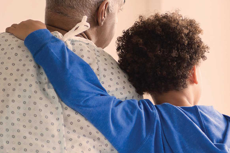 Child with arm around older male in hospital gown