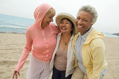 three middle aged women smiling and walking on beach