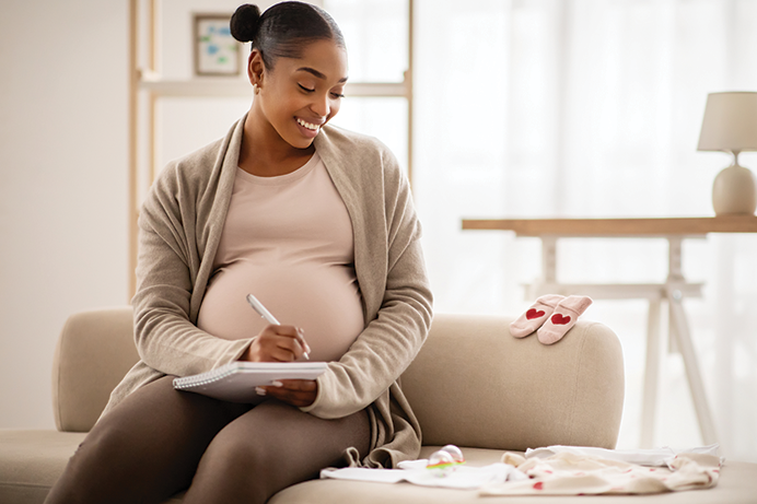 smiling pregnant black woman planning packing list