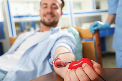 young man donating blood with focus on hand