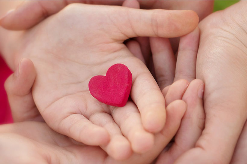 Child's hand holding a small red heart